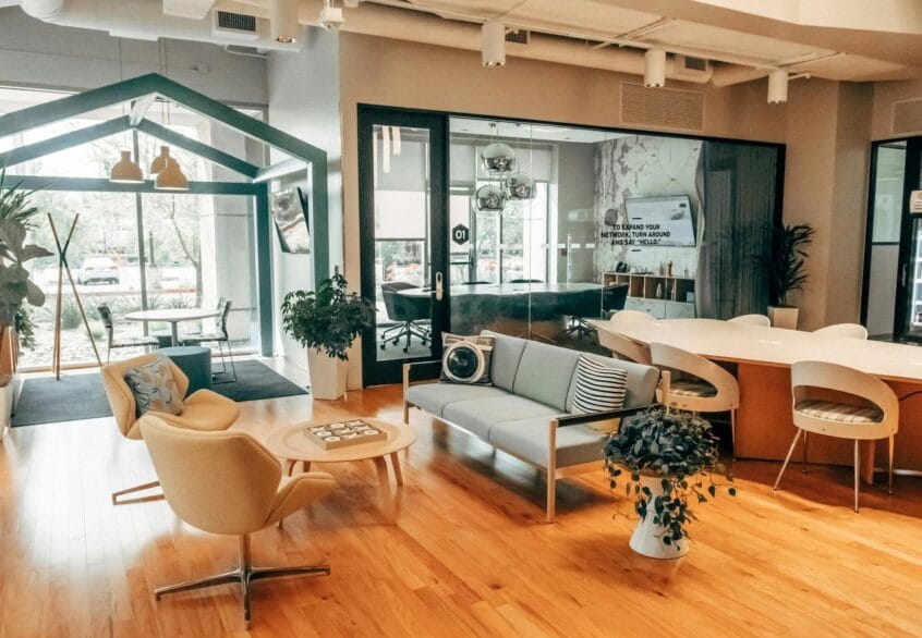 Optimisation Fiscale par le Placement Stratégique de Bureaux : L’Avantage Luxembourgeois 1 Zone de salon de bureau moderne avec des sols en bois clair, des fauteuils confortables et un coin détente douillet adjacent à une salle de réunion vitrée.