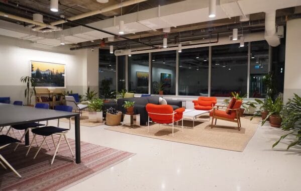Coin détente dans un espace de coworking avec canapés, fauteuils colorés, tapis naturels, plantes d’intérieur et une ambiance chaleureuse en soirée.