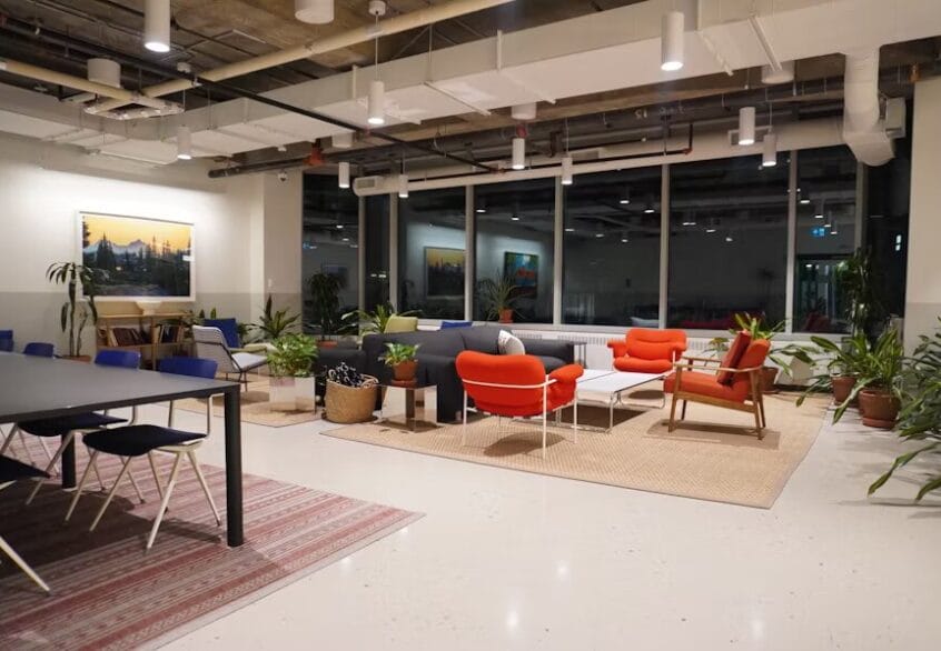 L’architecture au service de la productivité : quand le design des bureaux façonne le succès à Luxembourg 1 Coin détente dans un espace de coworking avec canapés, fauteuils colorés, tapis naturels, plantes d’intérieur et une ambiance chaleureuse en soirée.