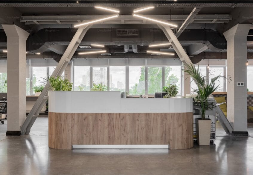 Trouver le bon type de bureau à louer à Luxembourg : un choix stratégique pour votre entreprise 1 Comptoir d’accueil contemporain en bois clair dans un espace de bureau ouvert avec luminaires design et plantes vertes